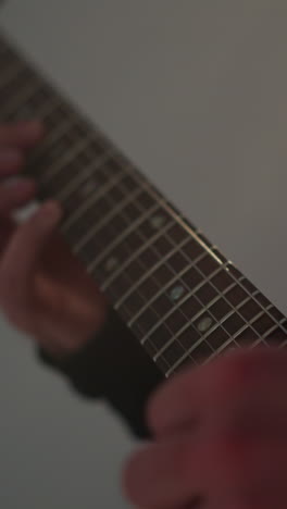 primer plano de una mano tocando una cuerda de guitarra roja contra un telón de fondo borroso