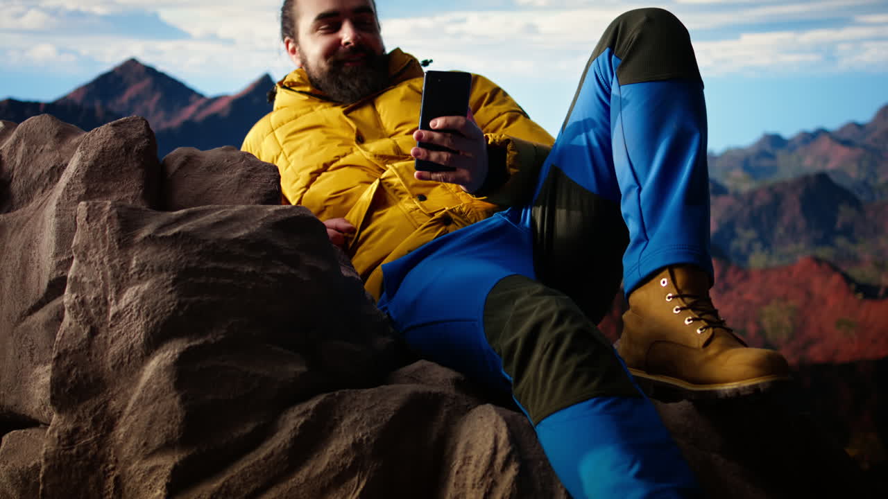 viajero con ropa cálida desplazándose por las redes sociales en la cima de la montaña