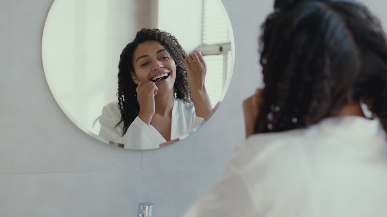Woman Flossing Her Teeth in Front of a Mirror