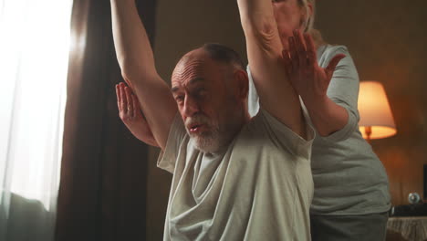 senior couple doing arm exercises at home
