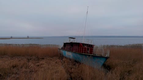 low fly over grass reeds with abandoned ship at dabie lakeshore in lubczyna, poland