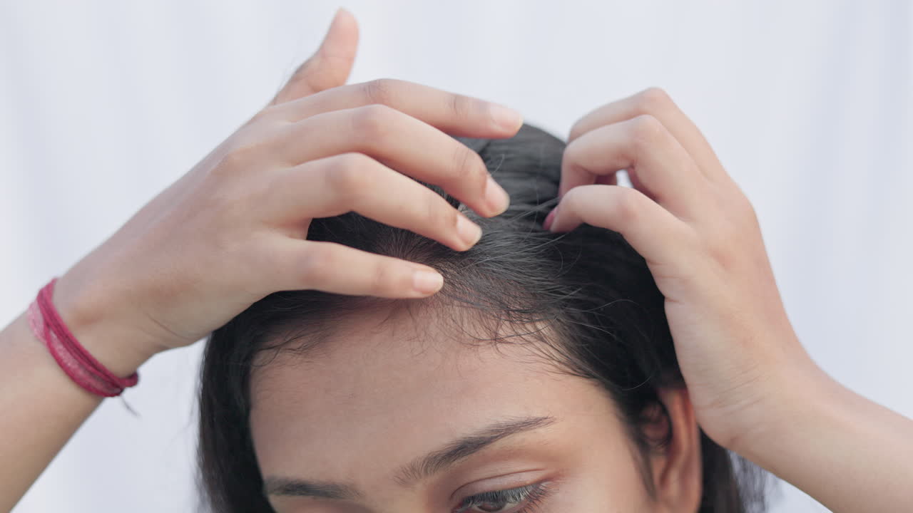 croped view of a women checking her receding hairline in white background