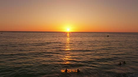 Aerial-shot-of-swimmers-enjoying-themselves-with-the-sun-setting-in-Iquique,-Chile