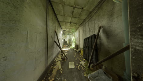 abandoned corridor with overgrown foliage and debris in a neglected building