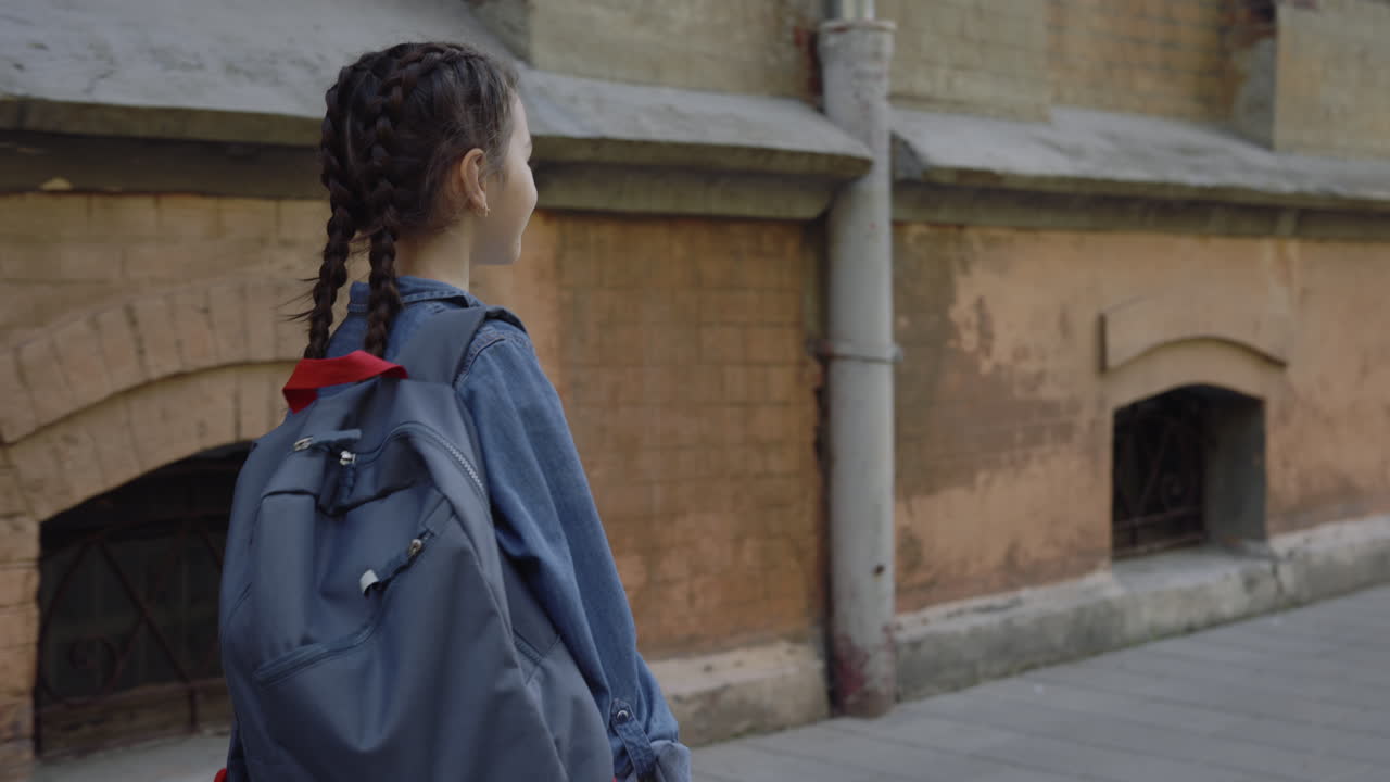 Girl with Backpack Walking Past Old Building