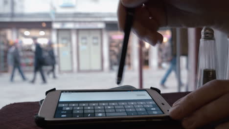 mujer escribiendo mensajes de texto con un nuevo número de teléfono en un café