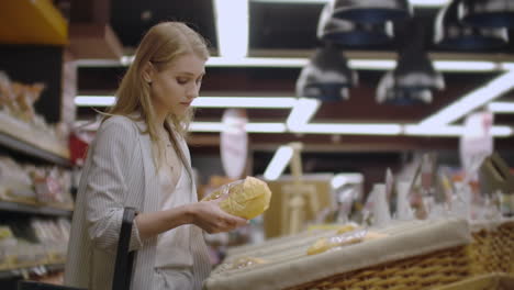 Venta-Compras-Consumismo-Y-Concepto-De-Personas---Mujer-Joven-Feliz-Eligiendo-Y-Leyendo-La-Etiqueta-Del-Pan-En-El-Mercado