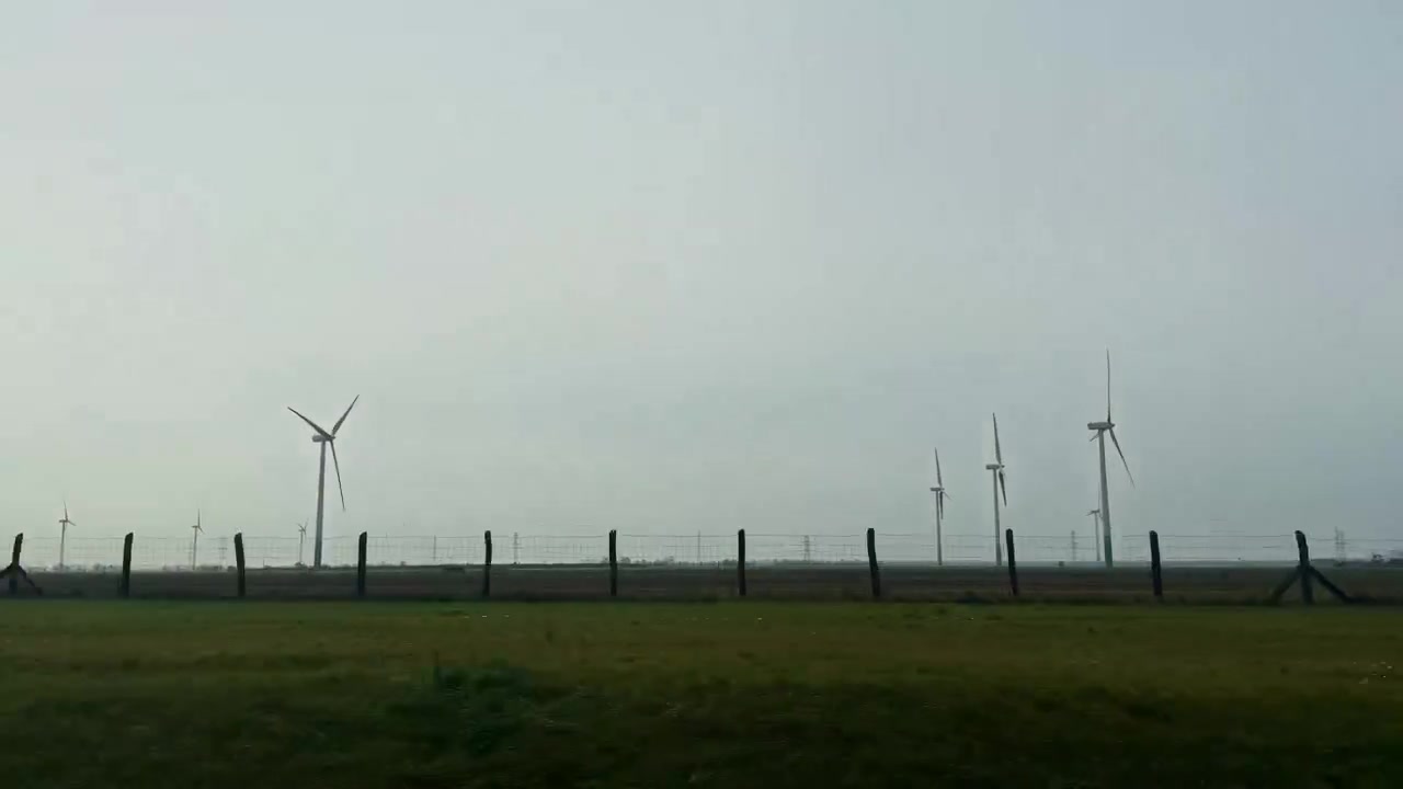 Billede fra sideruden af en vindmøllepark på grønne marker, der repræsenterer ren, vedvarende energi i Lillepolen, Polen.