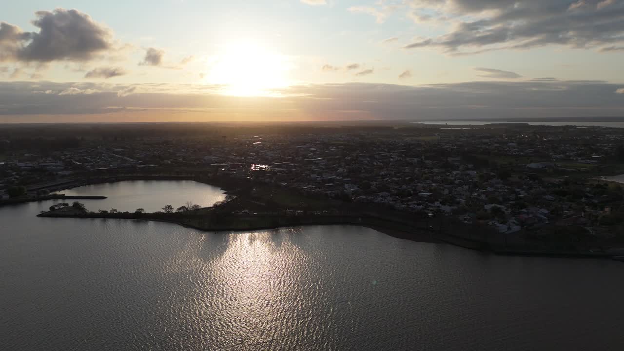 Aerial shot capturing the tranquil beauty of a sunset over an urban landscape with water reflecting the diminishing sunlight, creating a picturesque scene in Federacion, Entre Ríos, Argentina