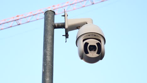 security camera on a pole with a construction crane in the background