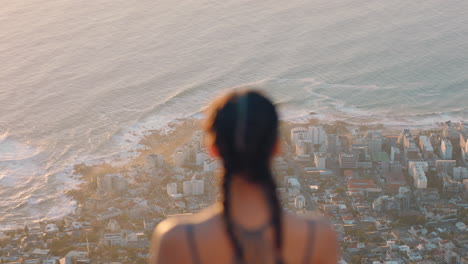 woman on mountain top looking at calm view of ocean at sunset girl standing on edge of cliff enjoying travel freedom