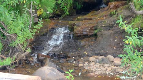 Waterfall-from-a-stream-flowing-over-rocks-creating-a-small-waterfall-on-beach-in-Kenai-Peninsula-of-Alaska