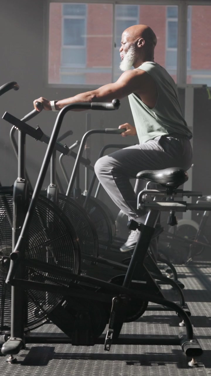 Senior Man Exercising on Air Bike in Gym