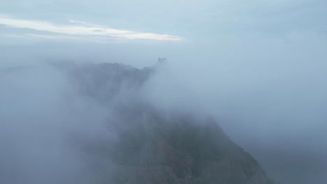 Ruins-on-mountain-peak-above-clouds-on-foggy-day