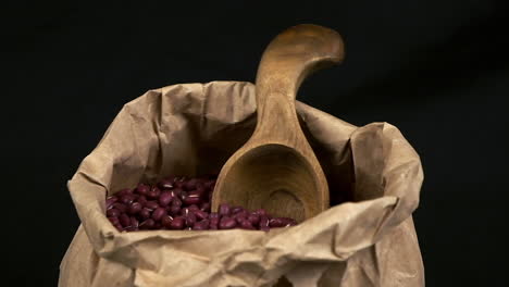 Paper-bag-of-dry-Adzuki-beans-rotate-in-dark-room,-macro-close-up