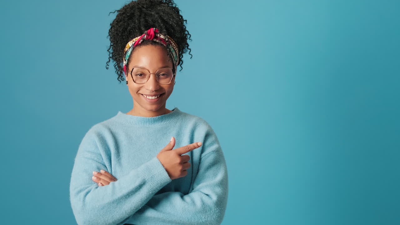 Jeune femme afro-américaine heureuse pointant vers un espace de copie