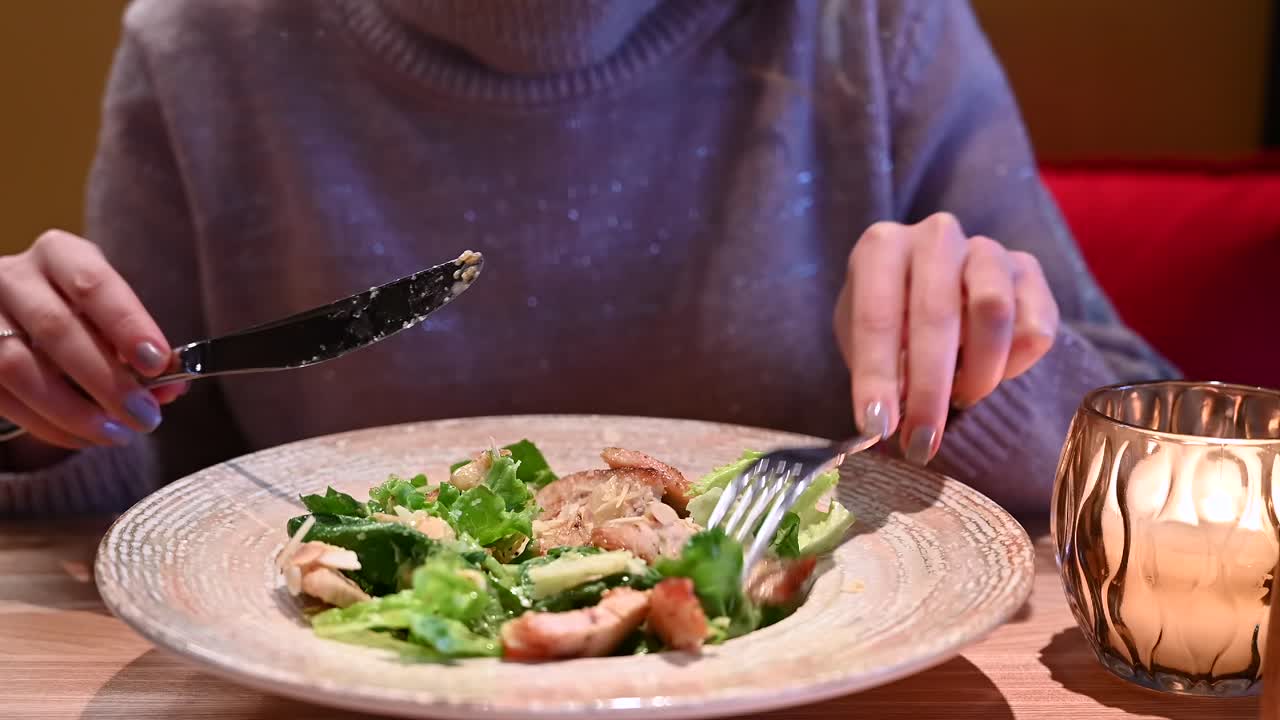Close up of a woman eating a caesar salad at a restaurant