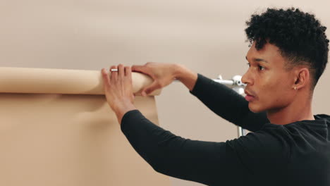 photographer setting up a beige backdrop in a studio