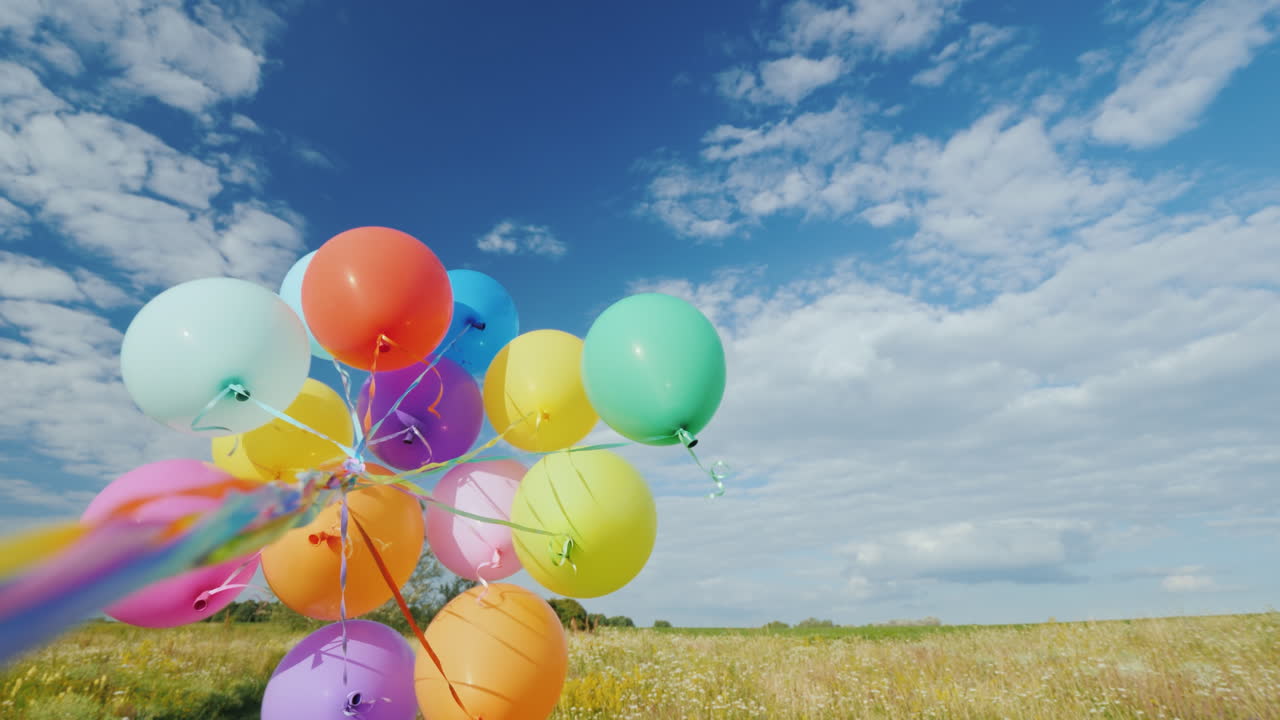 바람은 아름다운 푸른 초원을 배경으로 한 무리의 풍선과 놀아요