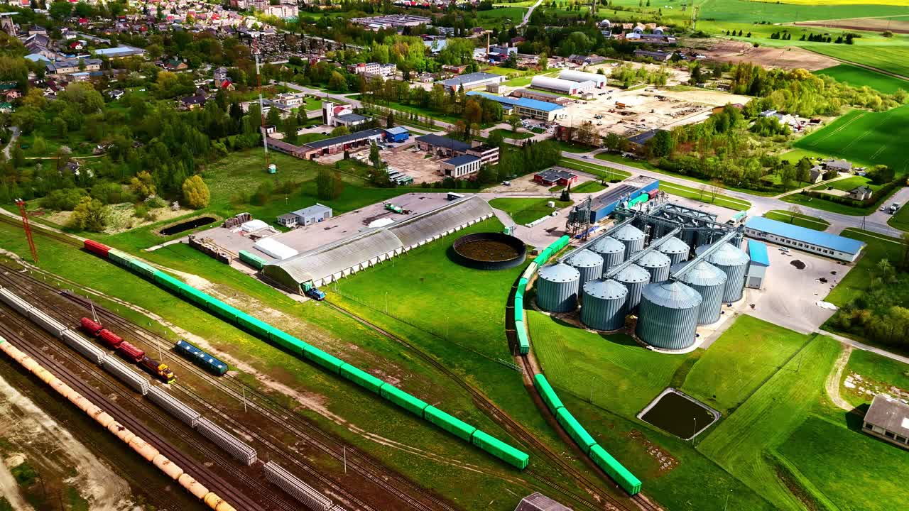 Wide timelapse of shadows moving over massive round silos near transport hub