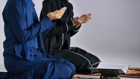 two asian muslim young women in traditional hijab are praying glorify allah and practicing the islamic faith in mosque.