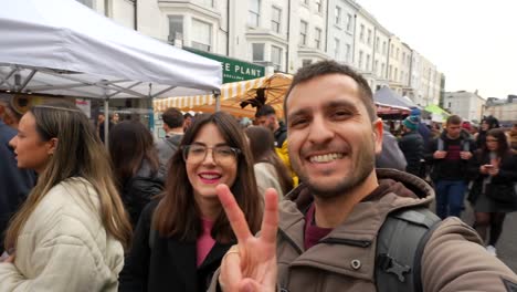 happy couple filming themselves walking through portobello road market, london. handheld