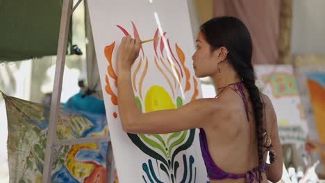 a woman paints a vibrant artwork on a canvas