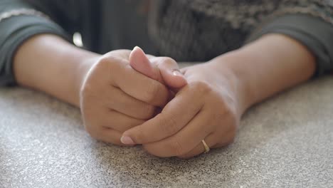 close up of a woman's hands clasped together on a table