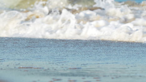 Gentle-waves-caress-the-sandy-beach,-creating-a-peaceful-and-rhythmic-seascape