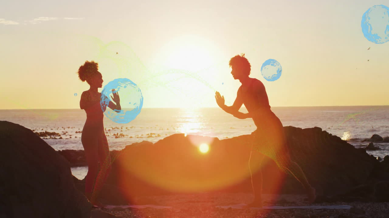 Playing with animation of globes, silhouetted people at beach during sunset