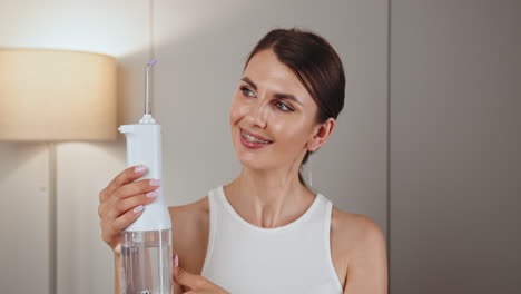 woman demonstrating a water flosser with braces