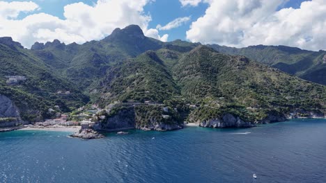 Vista-Aérea-De-Verdes-Picos-Montañosos-Rodeados-Por-El-Mar-Tirreno-Con-Un-Cielo-Azul-Claro-En-El-Fondo,-Costa-De-Amalfi,-Italia