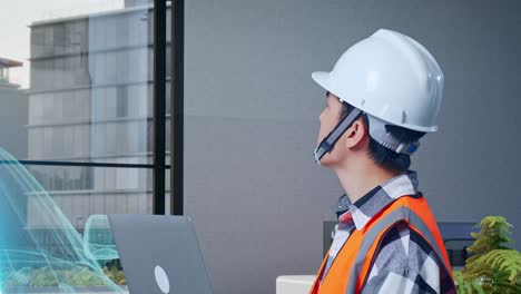 vista lateral de cerca de un ingeniero masculino asiático con casco de seguridad trabajando en una computadora portátil y mirando a su alrededor mientras está de pie con el concepto de vehículo eléctrico, instalación industrial de alta tecnología