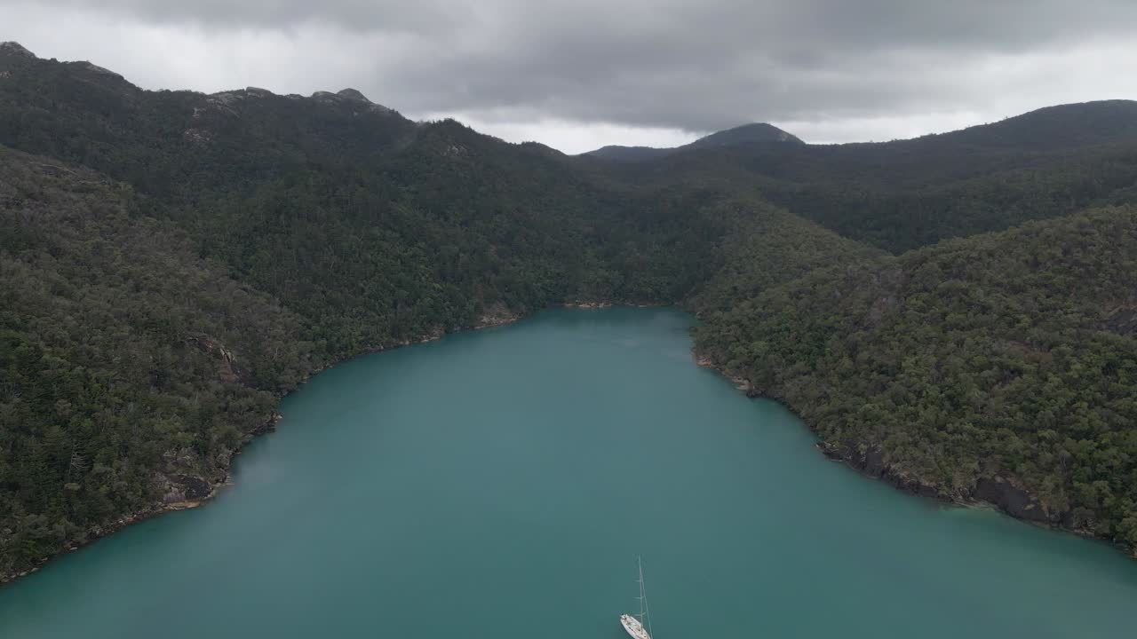 흐린 하늘이있는 후크 섬 근처의 나라 입구에 떠있는 범선 - whitsunday, qld, australia