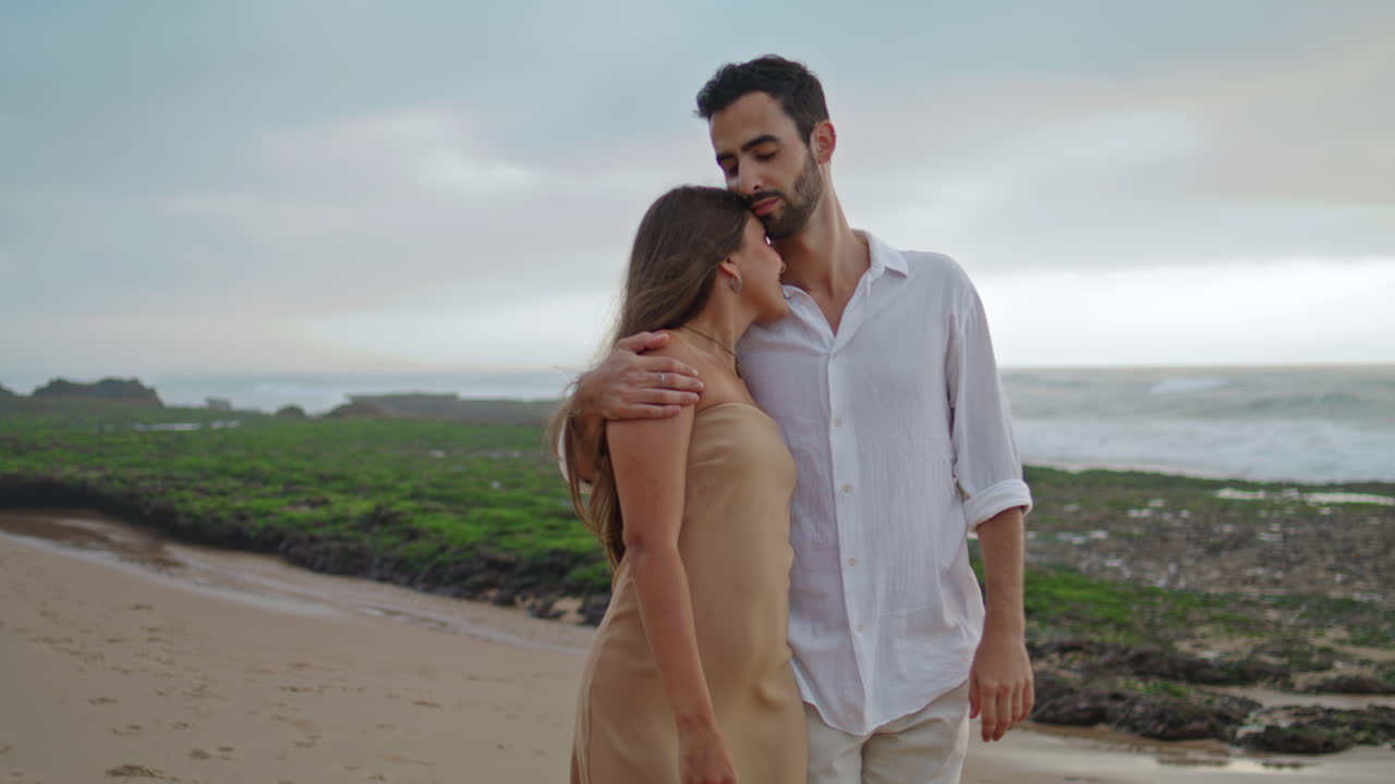 Carefree lovers walking on beach closeup. Man kissing woman tenderly vertically