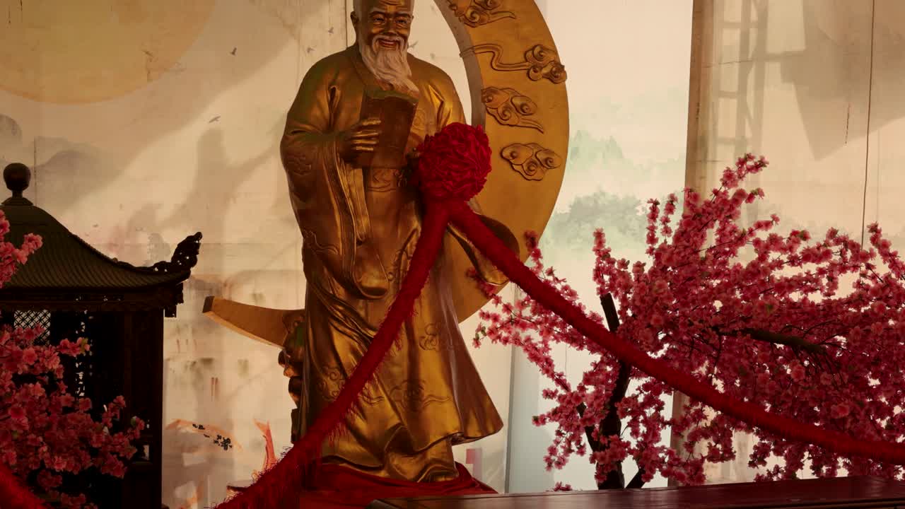 la estatua de yue lao adornada con una cinta roja vibrante
