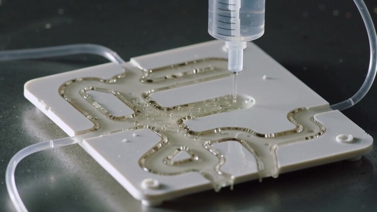 Siringa erogatrice che rilascia goccioline viscose a impulsi in una piastra microfluidica su un banco da laboratorio, riempiendo i canali.