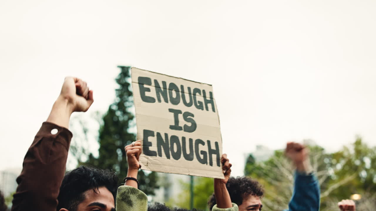 Protesters Holding 'Enough Is Enough' Sign with Raised Fists