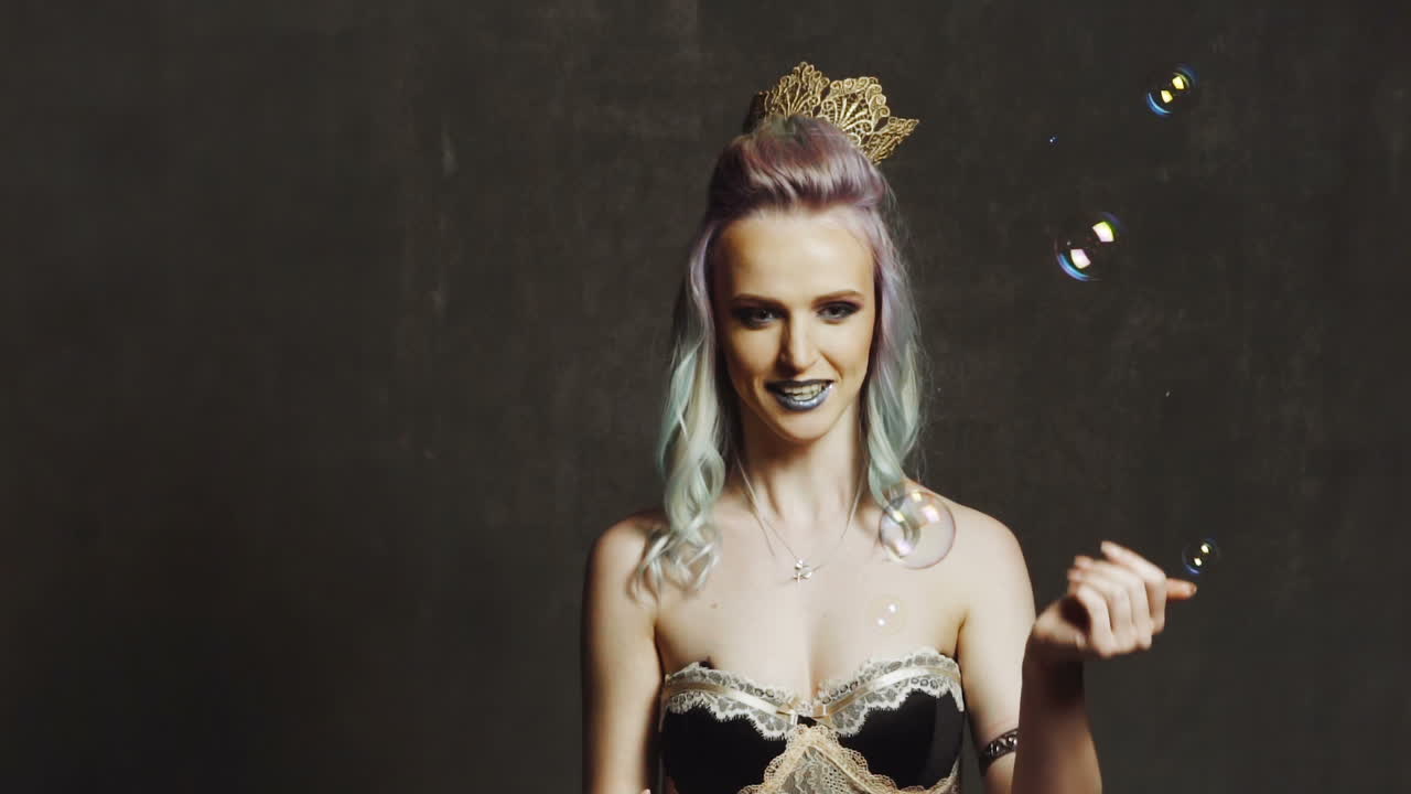 Woman with soap bubbles in studio. Fashion model with creative make up blowing soap bubbles in studio