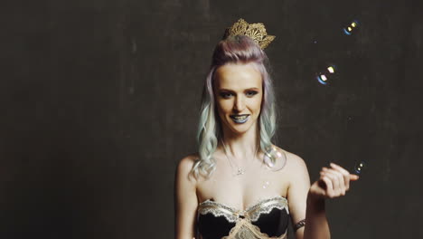 woman with soap bubbles in studio. fashion model with creative make up blowing soap bubbles in studio