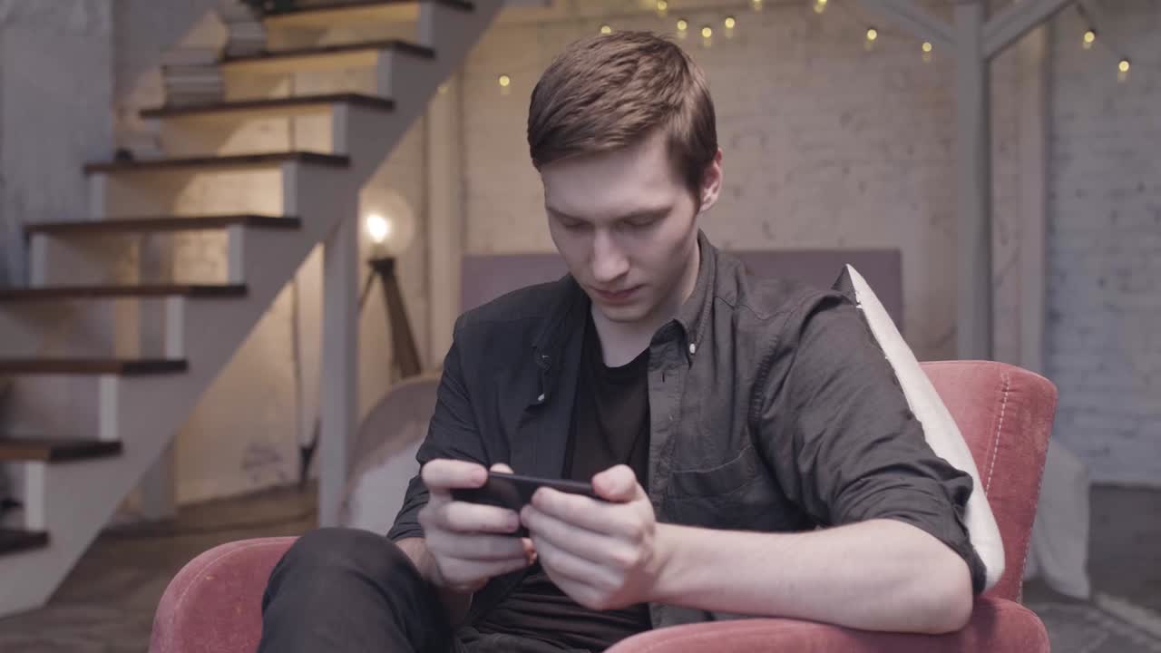 мужчина играет в мобильную игру дома.