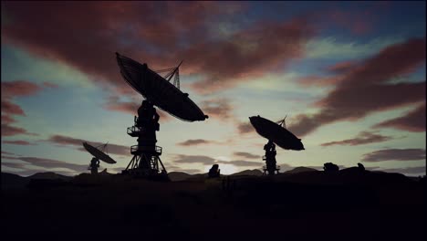 satellite dishes on field against cloudy sky during sunset