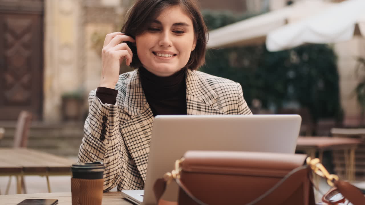 Businesswoman working on laptop in cafe outdoor.