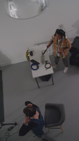 vertical video overhead shot of actors rehearsing movie or video scene in studio with film camera and sound crew