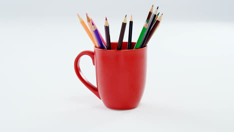 lápices de colores guardados en taza roja