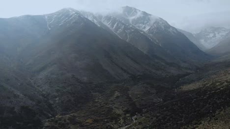 Aerial-ascending-next-to-giant-mountains-on-a-cloudy-day-at-the-Andes,-Chile-4K