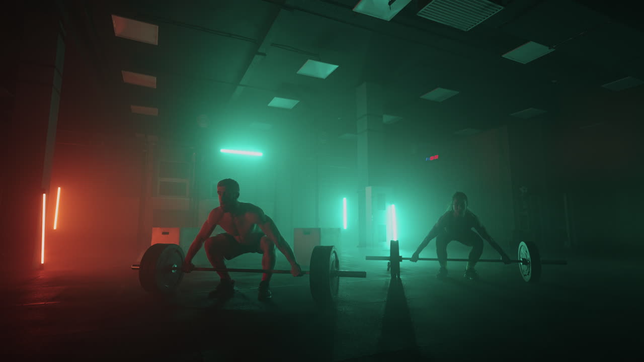 мужчина и женщина вместе поднимают штангу над головой, выполняя упражнение от тяжелой атлетики. сильные люди в цветном неоновом световом поезде