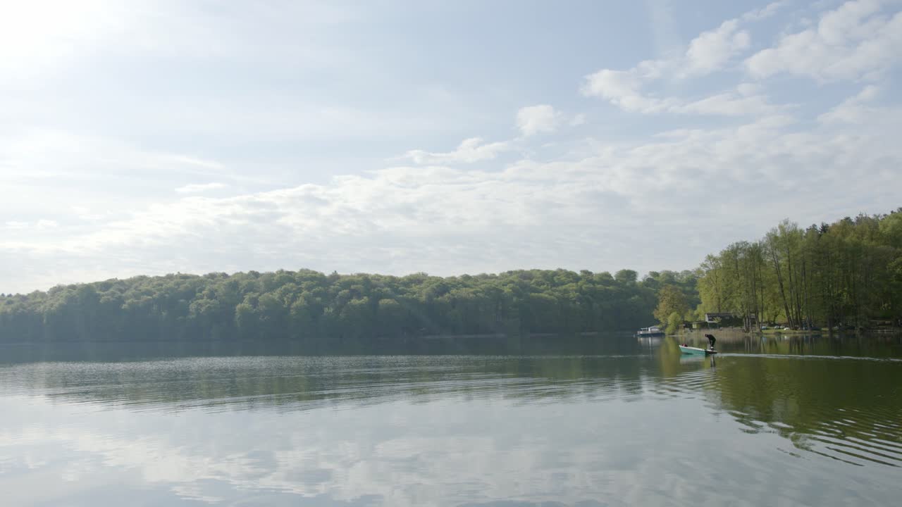 화창한 날 호수에서 움직이는 모터보트에 서 있는 남자