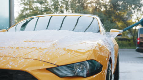 coche amarillo recibiendo espuma aplicada para el detallado