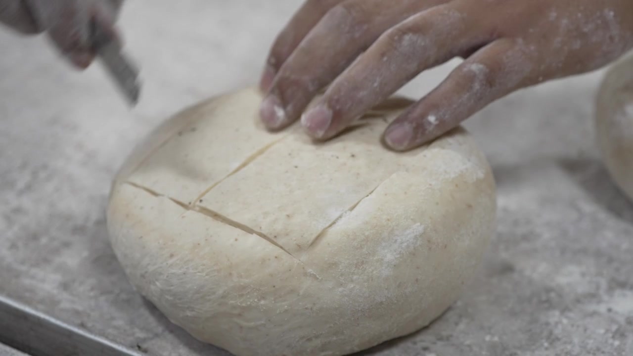 A woman rolling dough in a private bakery, captured in 4K resolution at 60fps, slow motion.